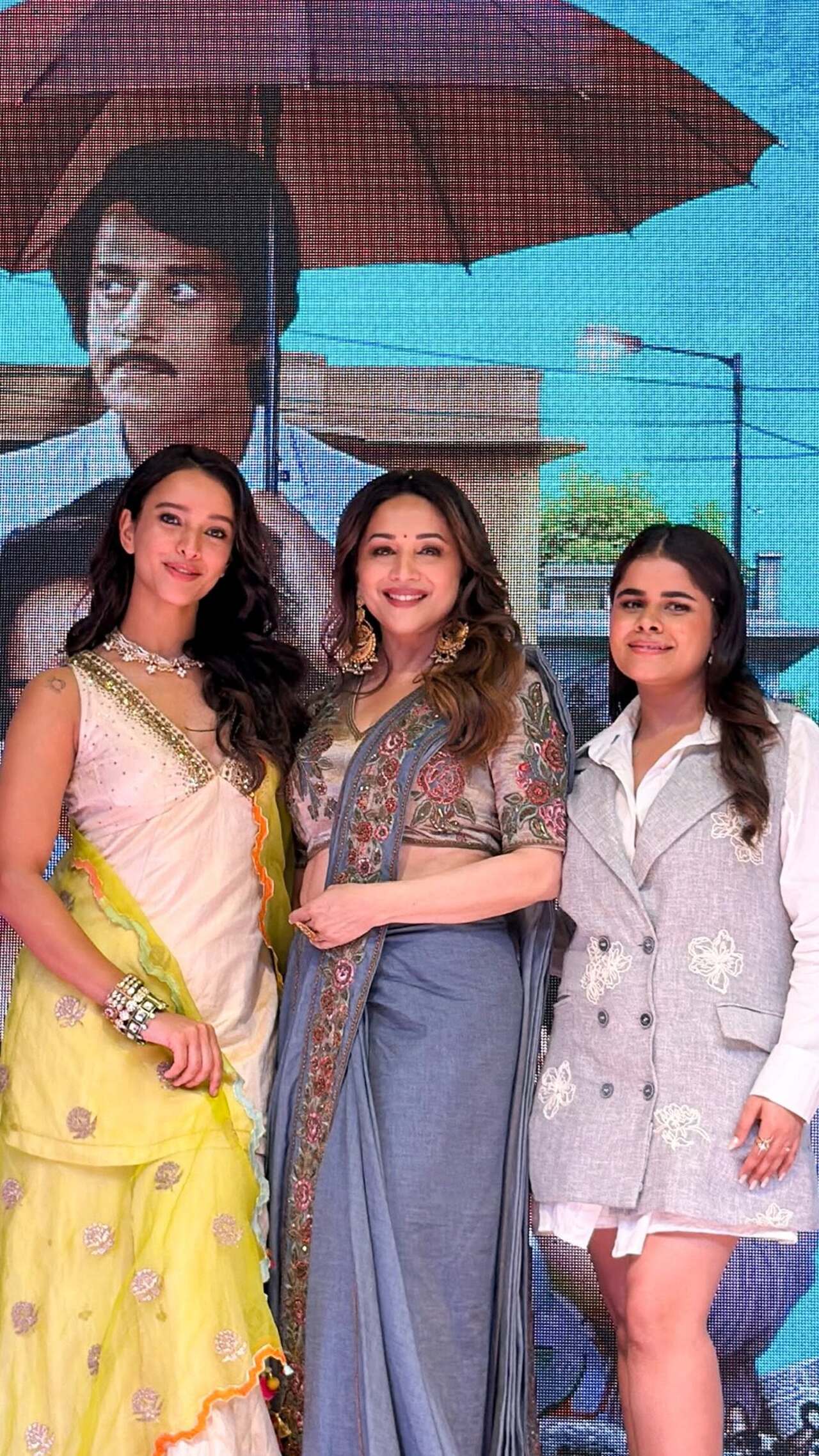 Madhuri Dixit displays timeless grace in a muted grey saree featuring intricate, colorful floral embroidery along its borders. She pairs the elegant drape with a heavily embellished blouse.